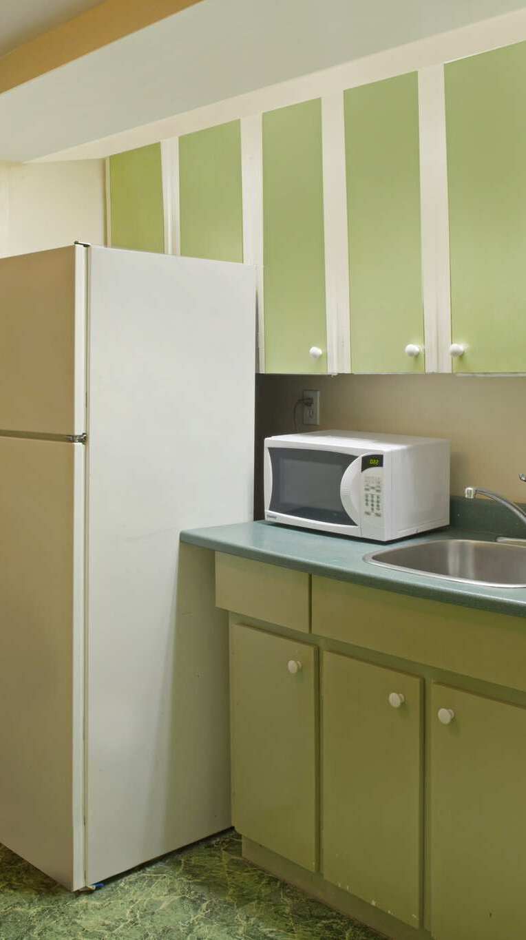 Guest room kitchen area with a fridge, stove, and microwave